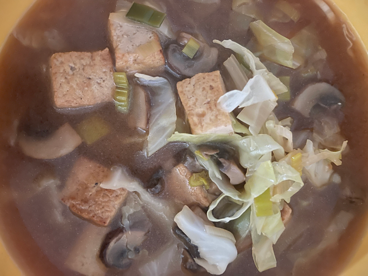 a bowl of cabbage soup with mushrooms and tofu